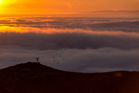 冰岛日落时在云海之上的山脊上的一图片