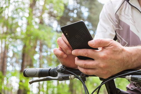 手机在乌克兰一个骑自行车穿过森林的人手中图片