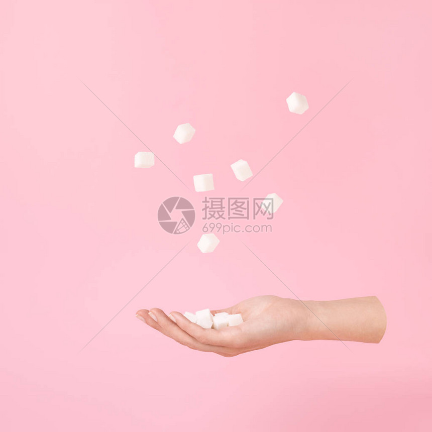 雌手和糖的立方体飘浮在粉色糊面上图片