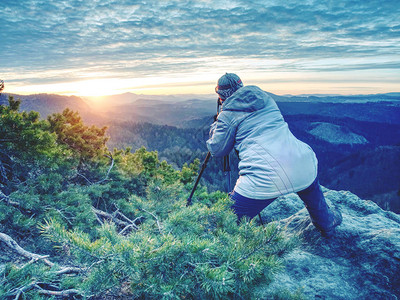 女登山徒和摄影师在深雾谷上的岩石上架设了三脚架图片