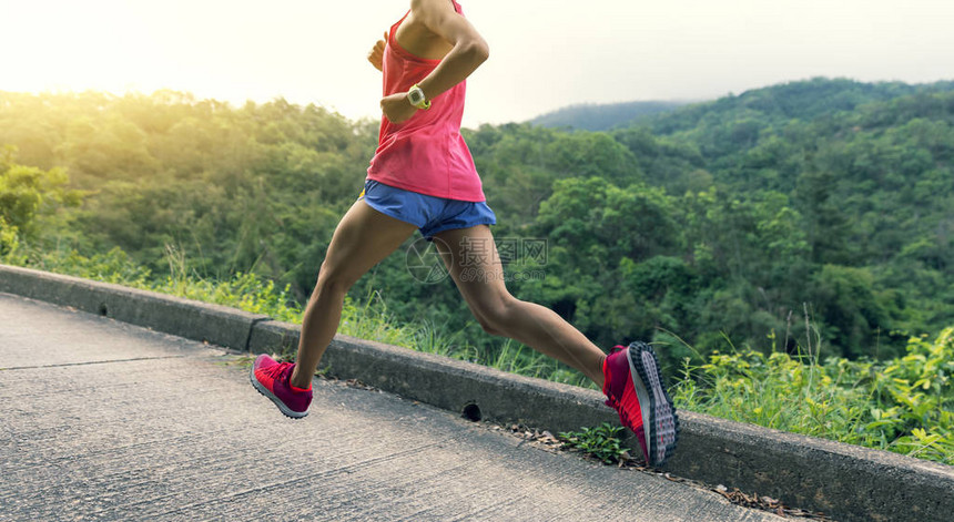 身穿服在森林山路上跑步的体育女员图片