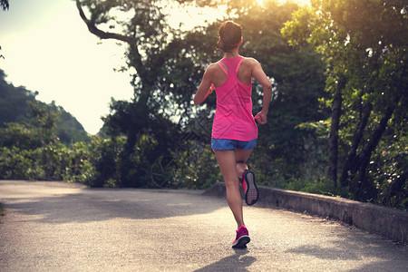 身穿运动服在森林路上跑步的体育女青年女子图片