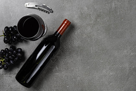 酒瓶玻璃开瓶器和葡萄放在混凝土背景图片