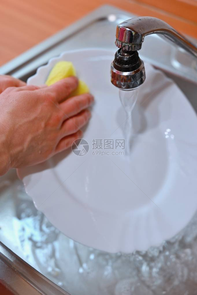 手洗盘子手拿海绵在厨房里下水洗图片