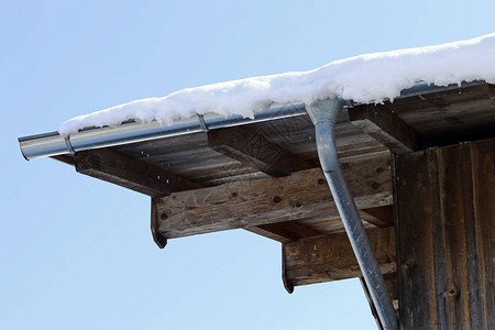 冬天有雨水槽的木屋木帽子上的排水沟图片
