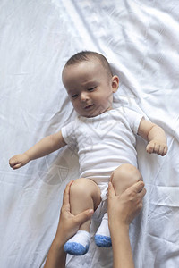 足内翻新生儿按摩妈和孩子一起做体操妈给她可爱的男婴按摩移动宝的腿背景
