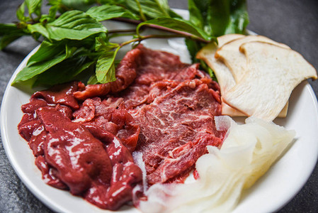 白盘上的肉食牛肉切片肝脏和蘑菇蔬菜图片