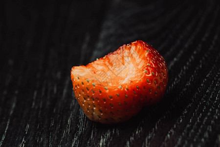 黑色木质背景上被咬的草莓特写图片