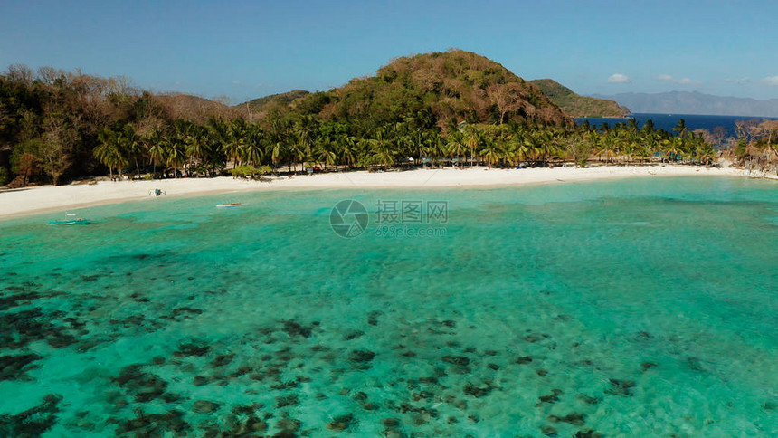 鸟瞰海滩与热带岛屿上的游客棕榈树和清澈的蓝色海水图片