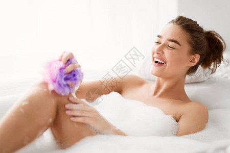 妇女与海绵在洗澡时洗脚用泡沫洗浴图片