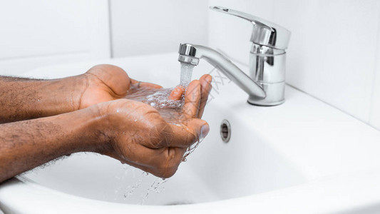 非洲人在自来水下洗手在浴室复印空间的背景图片