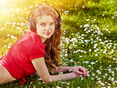 耳机女孩在绿色草地上捕捉着节奏音乐图片
