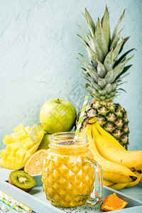 含有热带水果香蕉橙色芒果菠萝基维和玻璃中奇阿种子的黄冰沙图片