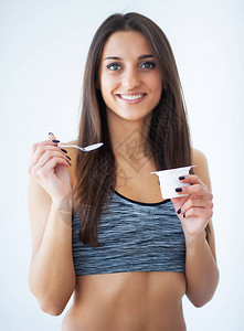 饮食快乐的年轻女人在厨房里吃酸奶图片