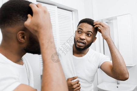 千百年的非洲男子摸他的头发眉毛和在浴室里照镜子图片