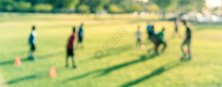 全景图模糊了一群拉丁美洲孩子在公园的绿色足球场上踢足球图片