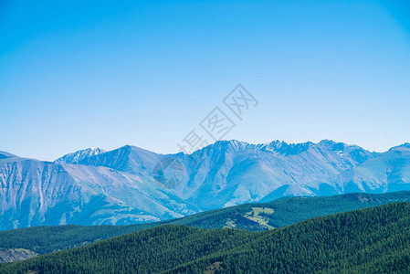 山上的巨山和冰川与森林蓝色晴朗的天空下的雪山脊高地的雪峰永久冻土图片