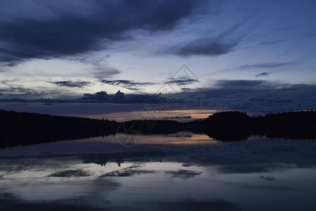 森林湖上的宁静日落水中倒映着云彩图片
