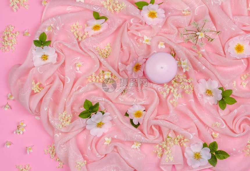 粉红色布背景上的白色和粉红色花朵和粉红色蜡烛的花组合物图片