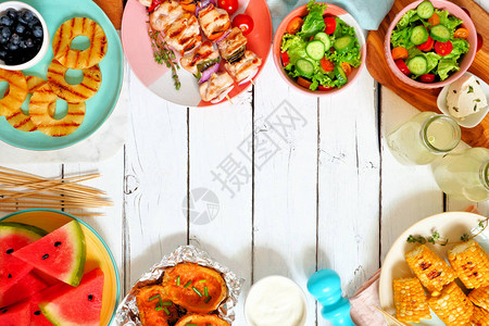 SummerBBQ或野餐食物框架选择烤肉水果沙拉和土豆对白木背景的俯视背景图片