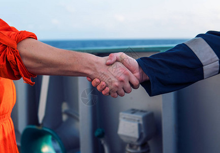 海洋承包商人与船上的工人握手图片