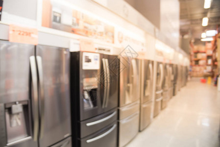 运动模糊了带有制冰机的法式门冰箱的广泛选择与家电设备行的模糊的零售店带有价格标签的背景图片