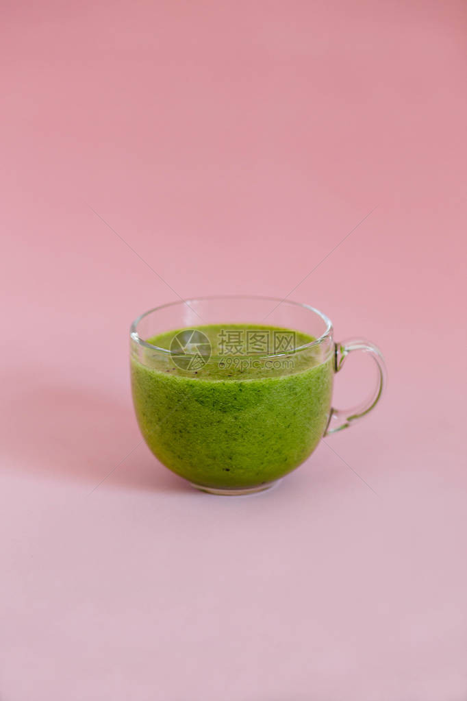 健康绿色的冰凉水在粉红背景的玻璃杯图片