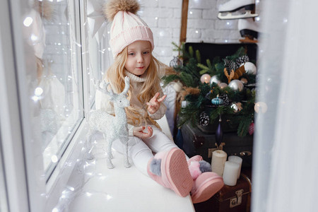 圣诞节早晨坐在窗台上的小女孩冬天的舒适浪漫时光概念圣诞快乐图片