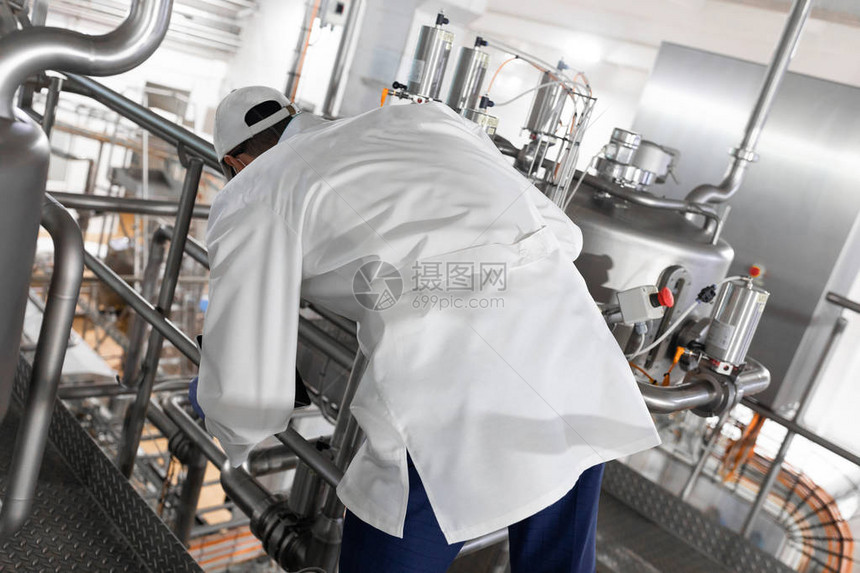 生产部工作人员站在乳品厂设备附近进行生产线架设图片