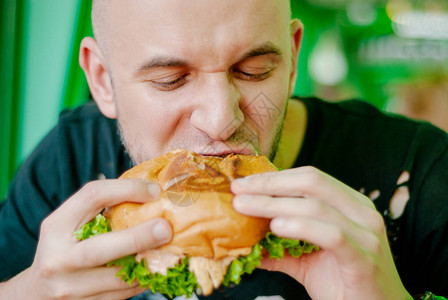 餐馆里的人吃汉堡包他饿了吃着好吃的口图片