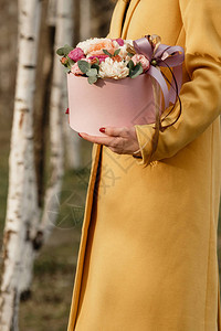 美女拿着带鲜花的粉红色盒子献给妇女节的礼物图片