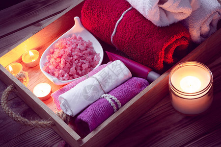 SPA由彩色毛巾粉红海盐和木质盘上蜡烛组成图片