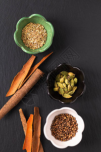 食品概念分类东方香料豆蔻荚芫荽籽茴香和肉桂皮棒在黑石板上图片