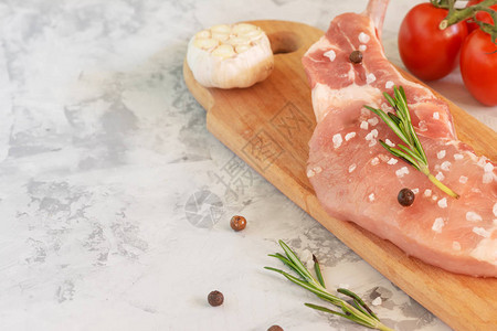 准备做饭用的牛排木制切板上有一块生猪肉西红柿和大蒜文本位图片