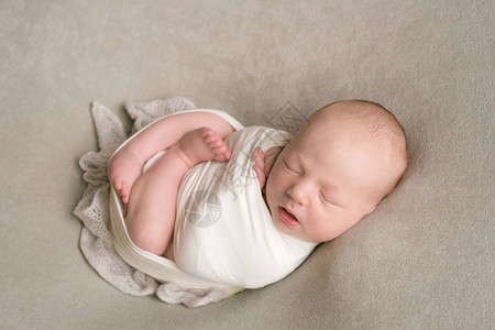 可爱的新生婴儿睡在一个篮子里穿着米色尿布的图片