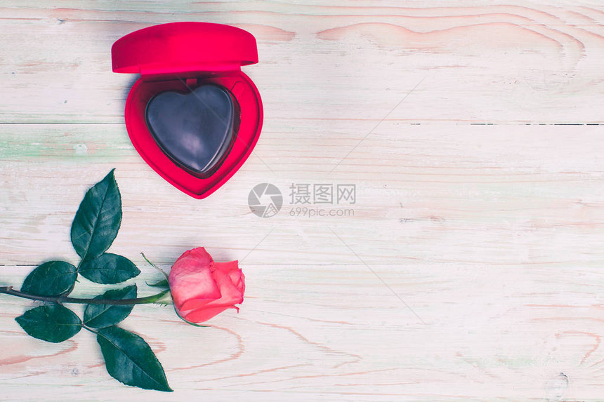 在开放的红色心形盒子里平躺着橙色玫瑰在木制背景图片