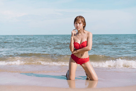 年轻漂亮感的亚洲女人穿着比基尼在海滩上享受图片