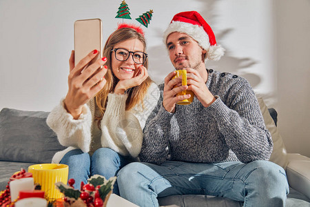 快乐的情侣享受圣诞节前夕与手机图片