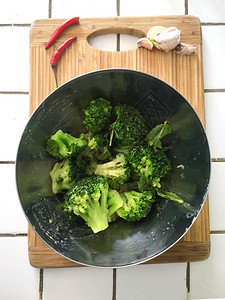 健康有机饮食素绿色西兰花在厨房白色瓷砖台面上的金属碗里图片