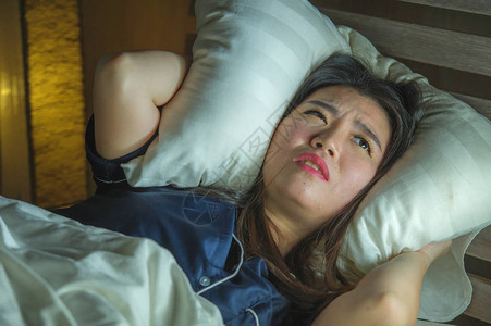 年轻美丽悲伤和沮丧的亚洲韩国女人深夜在床上醒来图片