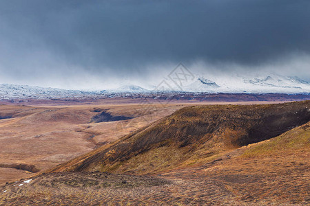 白雪皑的托尔巴奇克山和被云层覆盖的火山周围高清图片