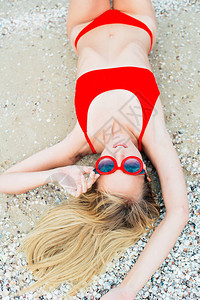 一个美丽的年轻女孩长头发穿红色泳衣在阳光明媚的热天在海图片
