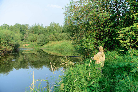 渔民男在河岸草中捕鱼图片