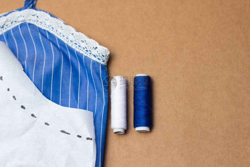 缝纫配件带蕾的蓝色布料测量胶带和Kraft纸背景图片