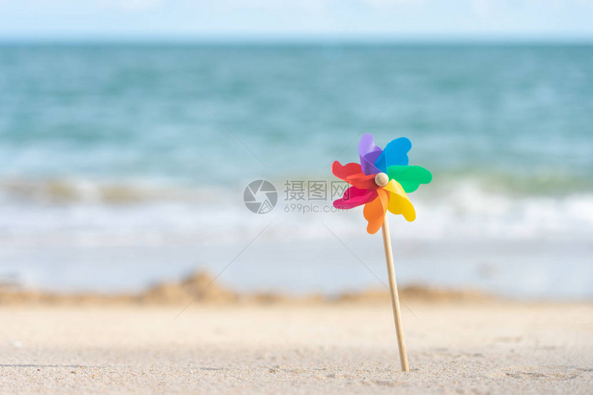 白天在海滩景上刺绣着多彩的风车纸蓝色背图片