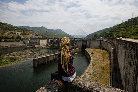 坐在山上一个发电厂旁边的女青年图片