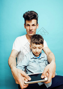 年轻漂亮的男人模特和可爱的小儿子在蓝色背景下一起玩耍图片
