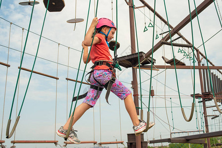 身着防护和安全服装的女孩穿过体育公园的吊桥图片