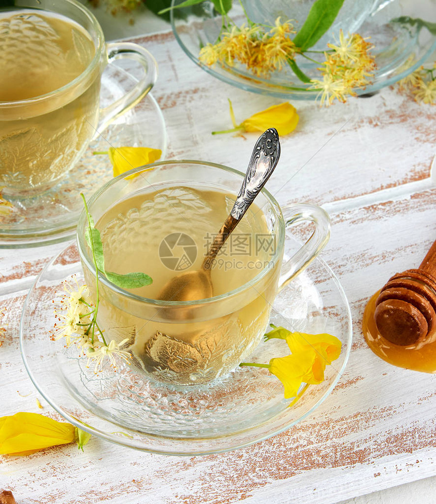 以透明茶杯由白木板上叶子的茶叶制图片