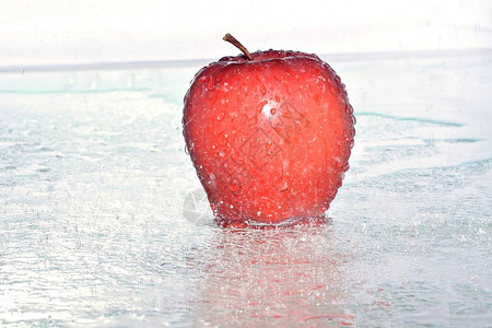 成熟的苹果在落白色背景上的水滴中图片